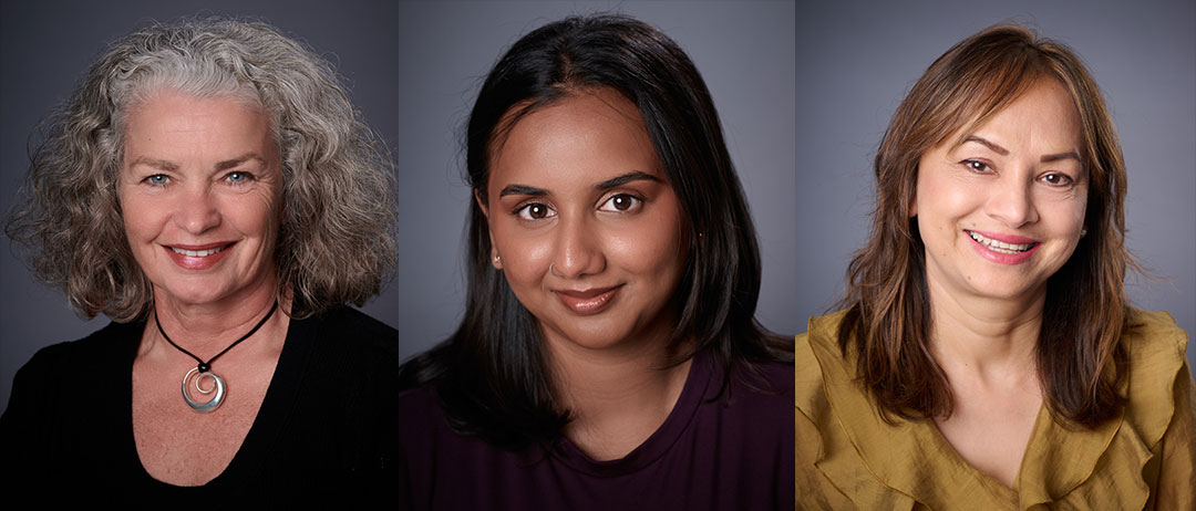 heashot-looks Three women pose for professional headshots against a gray background. The first has gray curly hair, the second has dark straight hair, and the third has light brown hair. All are smiling and wearing different colored tops.